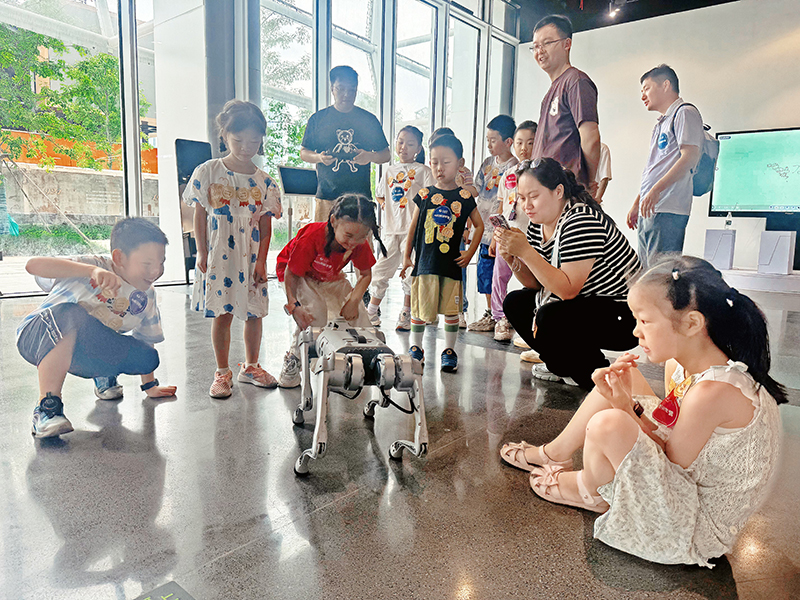 在人民网·梦幻灵境AI展演中心（武汉），小朋友们和机器狗互动