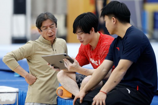 1月31日,张博恒(中)与中国男子体操队教练组组长金卫国(左)一起查看训练录像。新华社记者 王丽莉 摄