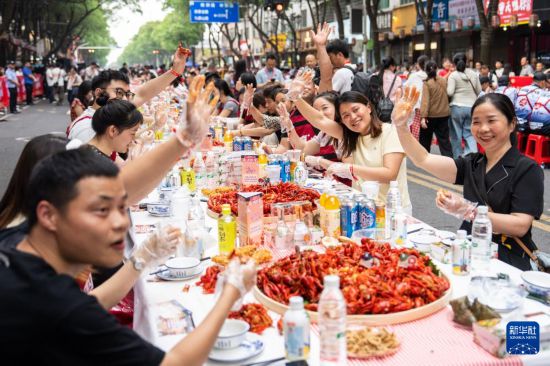 5月15日，在湖南南县沿湖路，游客品尝小龙虾。