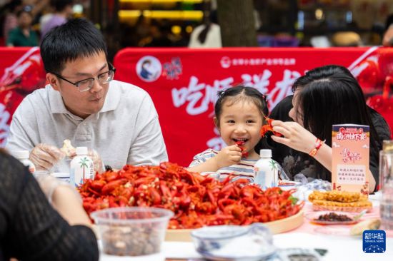 5月15日，在湖南南县沿湖路，游客品尝小龙虾。