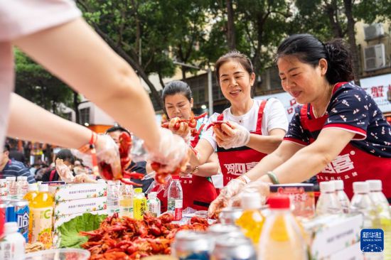 5月15日，在湖南南县沿湖路，游客品尝小龙虾。